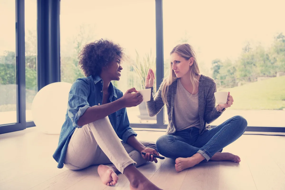 emotional intelligence in conversation — multiethnic women sit on the floor and drinking coffee