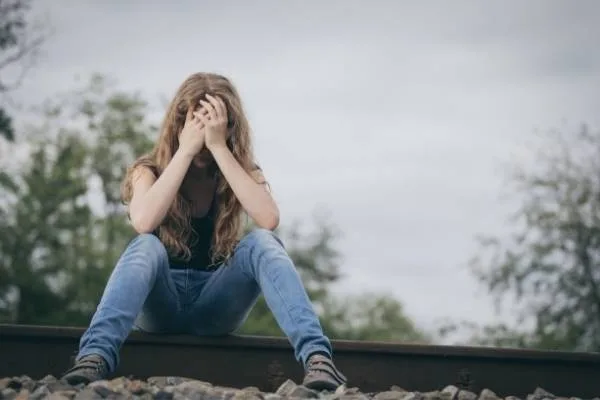A woman sitting on the train rail looking embarrassed - Boost confidence