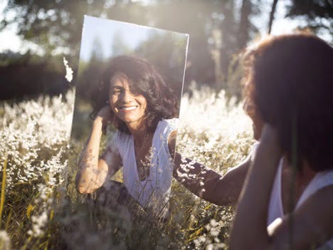 self love affirmations beautiful women smiling staring into a mirror in a open field