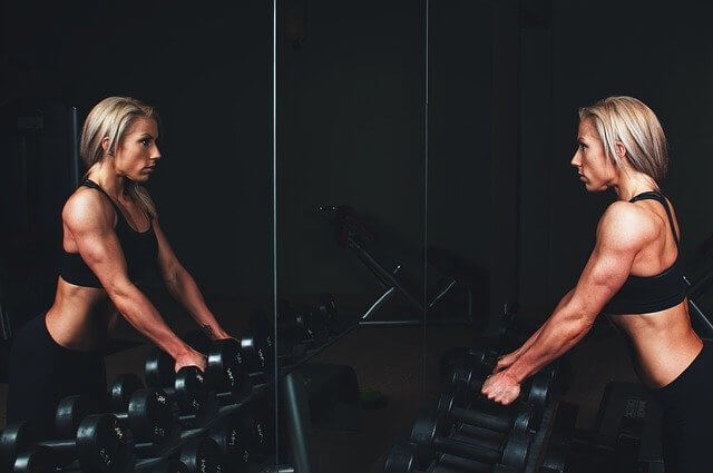 beautiful blond women in the gym staring in the mirror concept of Self-love techniques