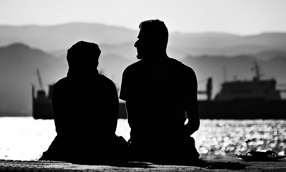 silhouette of a man attracted to a woman while sitting by the sea shore