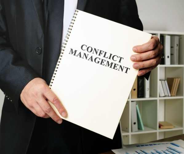 man holding a notebook marked Conflict Management