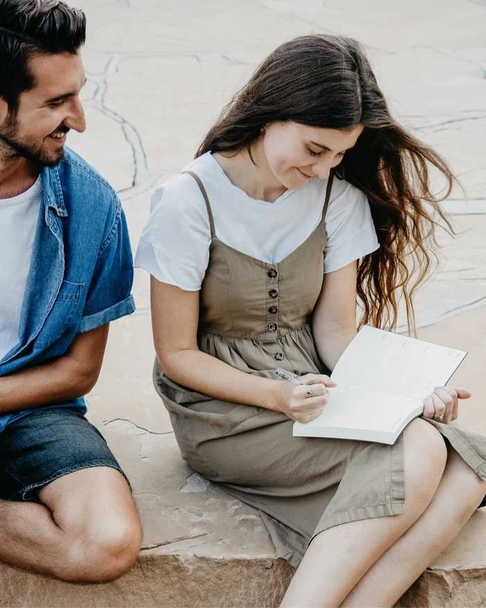 Man smiling to a woman who is writing on a planner
