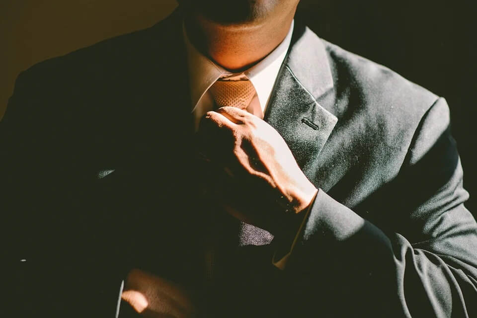 Man Fixing up his necktie - Why Confidence is important
