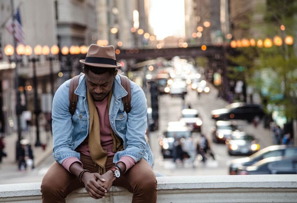 Sad man wearing a fedora sitting on a bridge