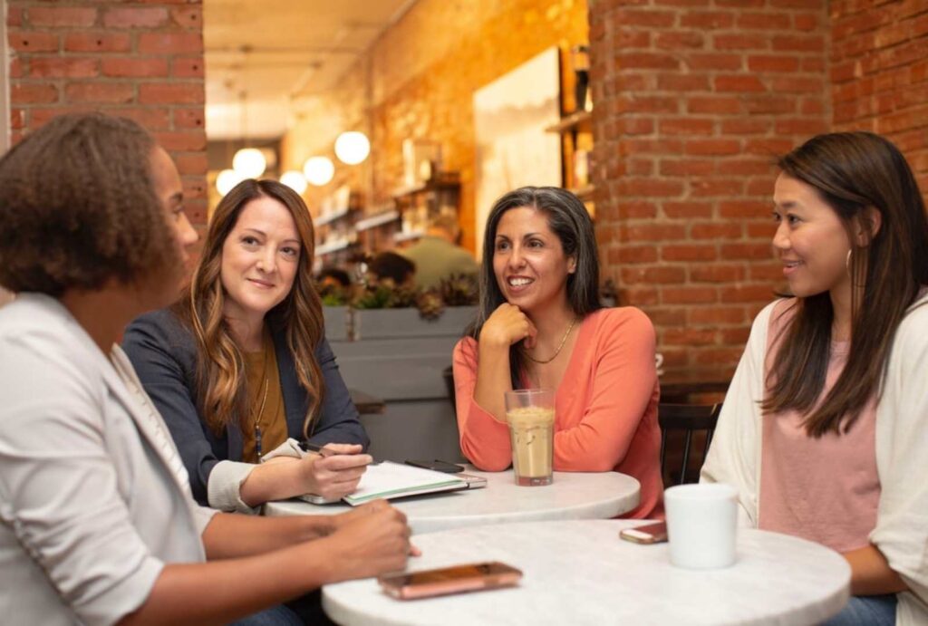 Group of people talking while sitting around dinner table - interpersonal and group communication