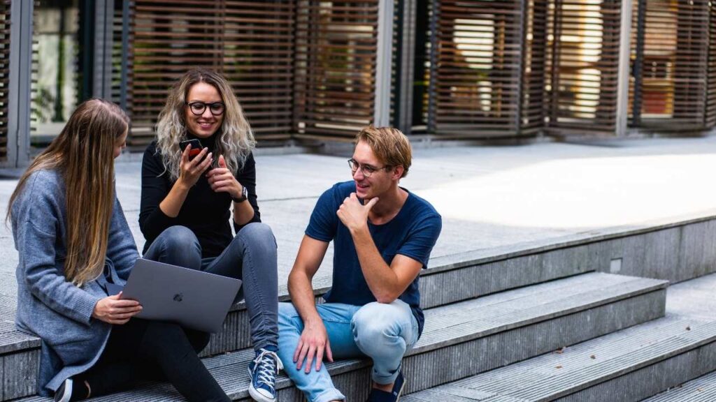 Three friends talking to each other while sitting on the stairs - how to improve conversation skills