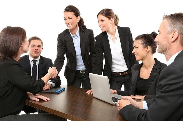 A Group of people in suits gathered around a table - Can a shy person run a business and be successful?