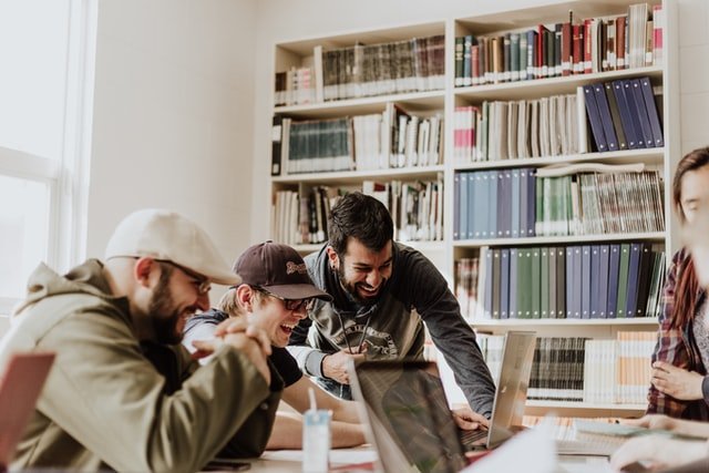 Three men laughing while in the library